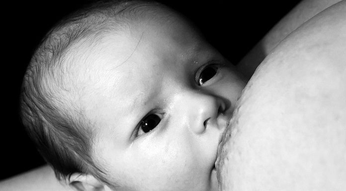 foto em preto e branco de um recém nascido mamando em um seio