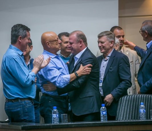 amin e merisio se cumprimentam sorridentes ao centro da fotos, com outros homens em volta