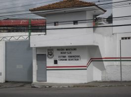 parte do portão de entrada de um presídio com guarita e inscrições do deap