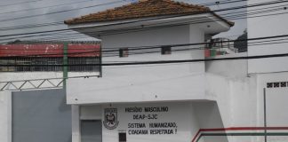 parte do portão de entrada de um presídio com guarita e inscrições do deap