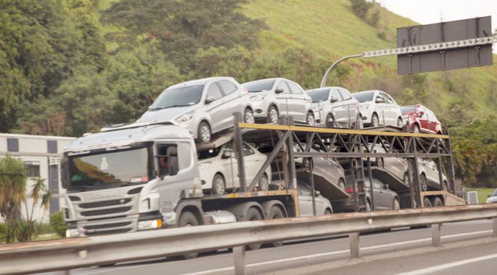 caminhão cegonha carregado cruza em velocidade uma estrada