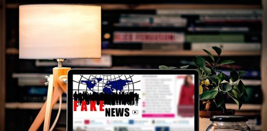 Como conter as “Fake News” notebook em cima de uma mesa com objetos onde se lê na tela "fake news"