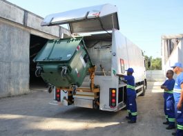 trabalhadores despejam grande conteiner em caminhão de lixo
