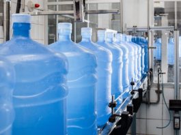 Vasilhame de água passa por padronização vasilhames de 20 litros dispostos em linha numa indústria