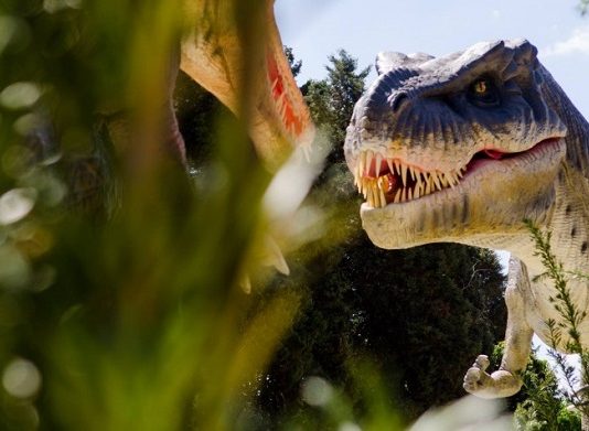 reproduçaõ realista de um dinossauro carnívoro no meio da vegetação