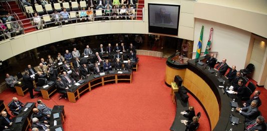 plenário da assembleia visto de cima com bancadas circulares e pessoas sentadas em sessão