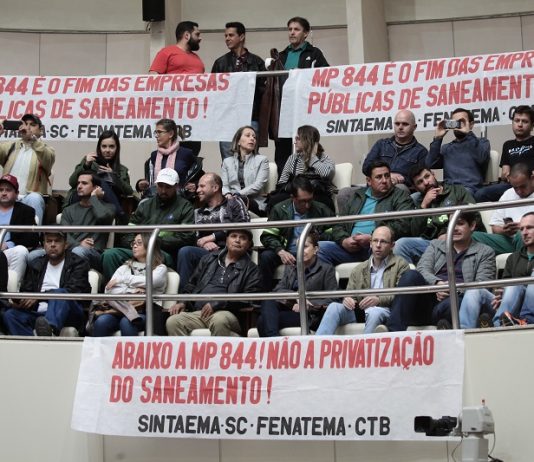 público diverso sentado em auditório superior da alesc com faixas contra a privatização e a mp
