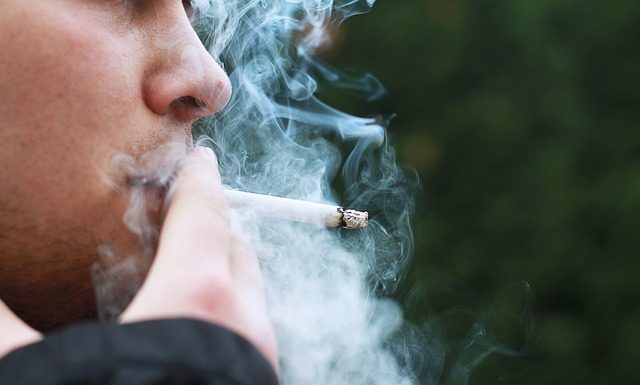 close no rosto de um homem fumando um cigarro com um excesso de fumaça saindo
