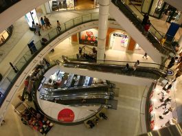 vão central de escadas rolantes de um shopping visto do piso superior mostrando os níveis inferiores e pessoas ciruclando