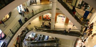 vão central de escadas rolantes de um shopping visto do piso superior mostrando os níveis inferiores e pessoas ciruclando