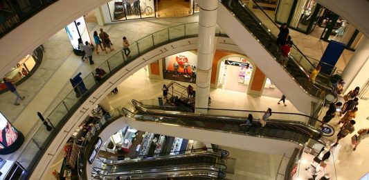 vão central de escadas rolantes de um shopping visto do piso superior mostrando os níveis inferiores e pessoas ciruclando