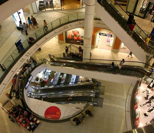 vão central de escadas rolantes de um shopping visto do piso superior mostrando os níveis inferiores e pessoas ciruclando