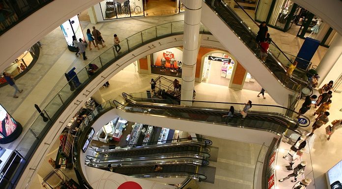 vão central de escadas rolantes de um shopping visto do piso superior mostrando os níveis inferiores e pessoas ciruclando