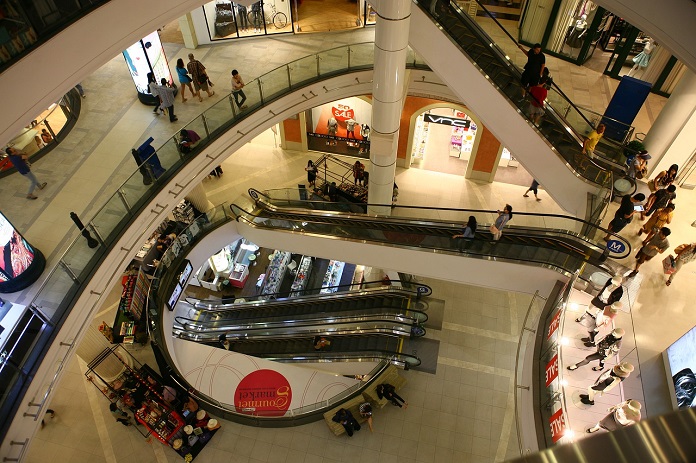 vão central de escadas rolantes de um shopping visto do piso superior mostrando os níveis inferiores e pessoas ciruclando