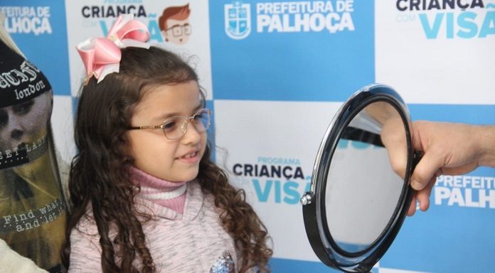 garota de aproximadamente 7 anos olha sorridente para um espelho usando óculos