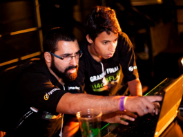 dois homens usando camisetas iguais olham para a tela de um notebook