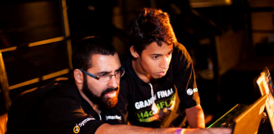 Florianópolis recebe maior festival hacker da América Latina dois homens usando camisetas iguais olham para a tela de um notebook