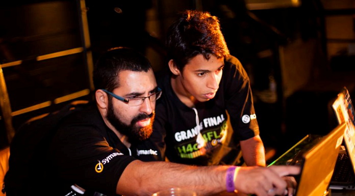 dois homens usando camisetas iguais olham para a tela de um notebook