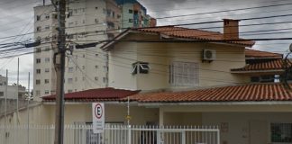 fachada da casa sede do igp em são josé; portão de grade e um poste na frente com muitos fios; alguns carros estacionados