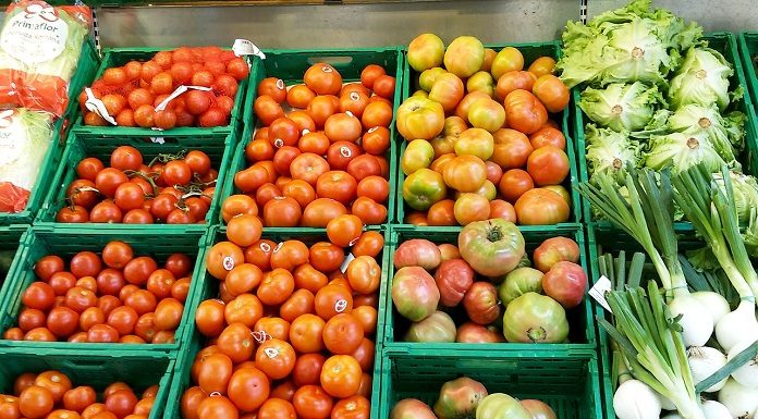 estande de legumes em supermercado com tomates de diversos tamanhos e outros legumes
