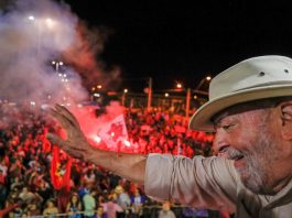 Justiça determina que Lula pague R$ 31 milhões no caso do triplex lula, de chapéu, acena para multidão do alto de uma plataforma