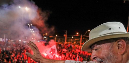Justiça determina que Lula pague R$ 31 milhões no caso do triplex lula, de chapéu, acena para multidão do alto de uma plataforma