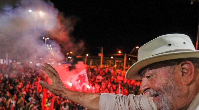 lula, de chapéu, acena para multidão do alto de uma plataforma