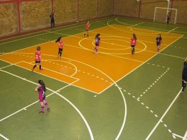 quadra de futsal onde estão jogando dois times de meninas