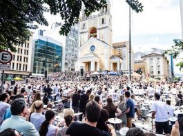 grande público em uma praã em frente a uma catedral assiste os vários bateristas