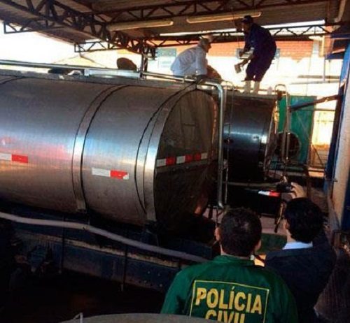 agentes da polícia civil examinam caminhões-tanque de leite estacionados