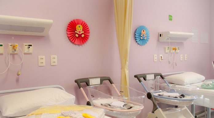 quarto da maternidade com duas camas, dois berços, equipamentos em volta e parede rosa