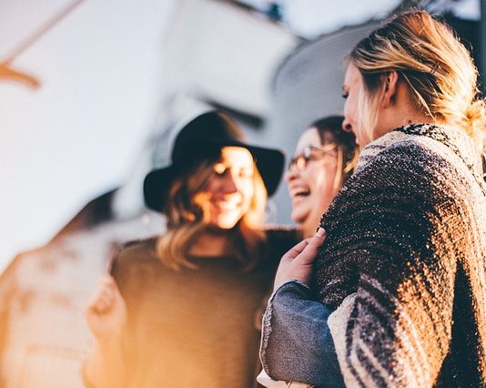 três mulheres dão risadas juntas