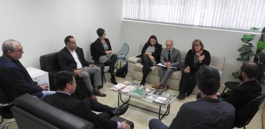 Udesc terá escritório de intercâmbio nos EUA grupo de homens e mulheres em reunião em uma sala com sofás e poltronas em volta de uma pequena mesa de centro ao lado de uma janela