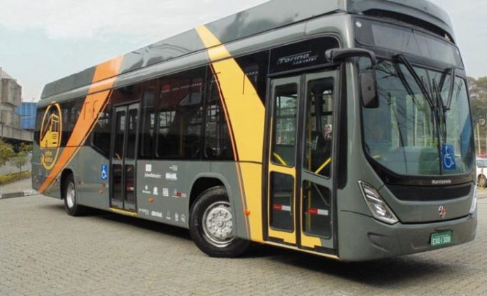 foto do ônibus elétrico. pintado de cinza e faixas amarelas; externamente é muito similar aos ônibus comuns