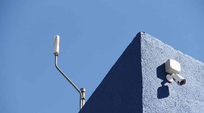 dois pequenos aparelhos sensores instalados em quina de uma parede no alto de um prédio, um em cada fachada
