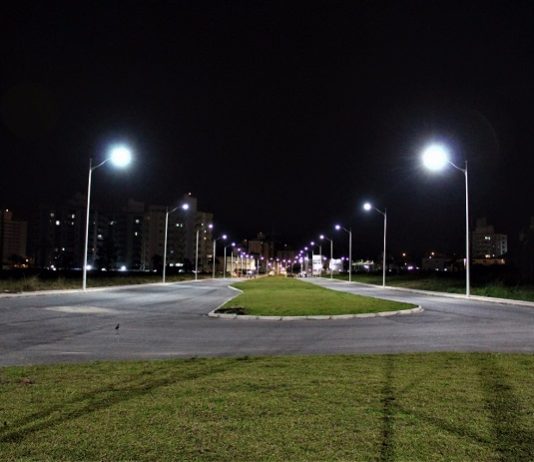 avenida larga, com canteiro central, vista vazia de noite com postes novos acesos