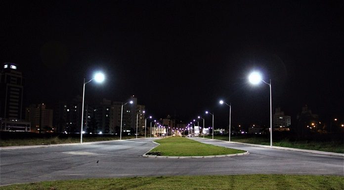 avenida larga, com canteiro central, vista vazia de noite com postes novos acesos