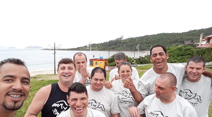 professor faz selfie com grupo de alunos da apae usando a camisa do projeto em área externa próxima ao mar
