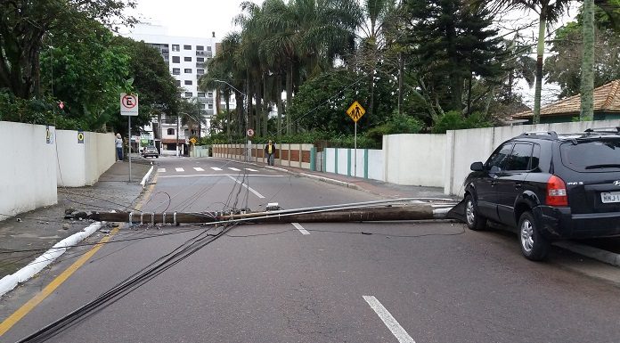 poste caído atravessado na rua, com carro suv em cima da calçada e fios espalhados