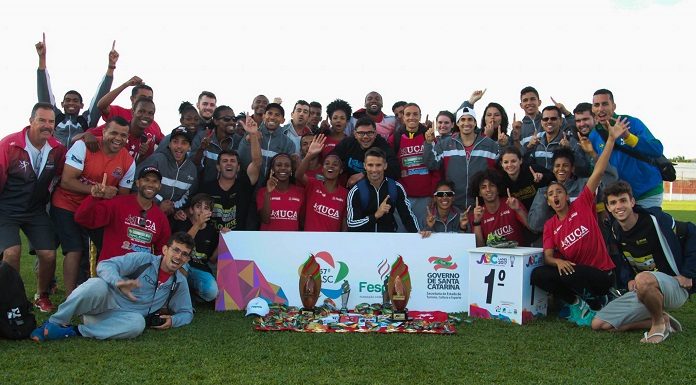 grupo de atletas posa mostrando medalhas em um gramado