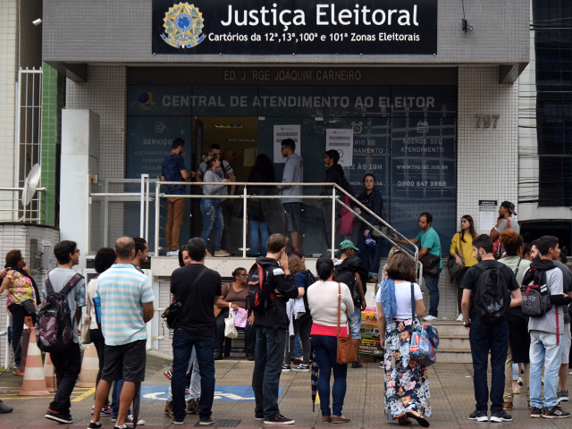 pessoas em fila na frente de cartório da justiça eleitoral para fazer cadastro biométrico