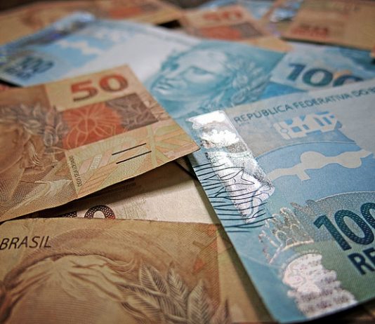 notas de 50 e 100 reais dispostas sobre uma mesa