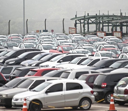 Emplacamentos de veículos registram alta de 14,3% em agosto pátio lotado e carros estacionados de diversos modelos; com um caminhão cegonha ao fundo