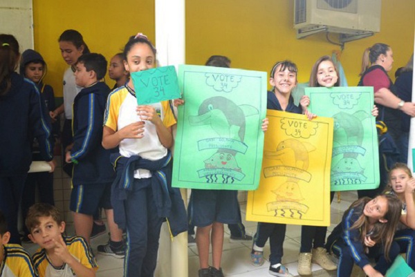 meninas mostram cartazes com os cadidatos