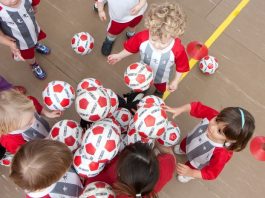 No sábado (15) tem aula de inglês e futebol grátis para crianças crianças pequenas com o mesmo uniforme tentam pegar bolas de um monte, vistas de cima em uma quadra