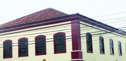 fachada do prédio de arquitetura portuguesa; alguns fios de energia passam na frente