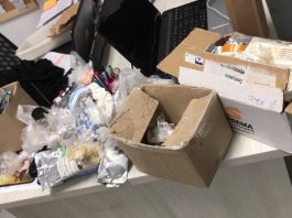 Polícia apreende remédios irregulares em farmácia de manipulação diversas caixas de papelão e embalagens abertas sobre uma mesa de escritório; tudo bagunçado