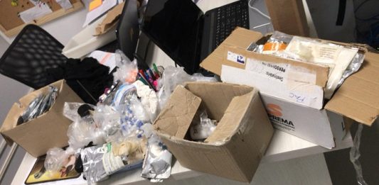 Polícia apreende remédios irregulares em farmácia de manipulação diversas caixas de papelão e embalagens abertas sobre uma mesa de escritório; tudo bagunçado