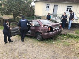 agentes de trânsito em volta de um veículo muito velho e enferrujado parado em uma ladeira