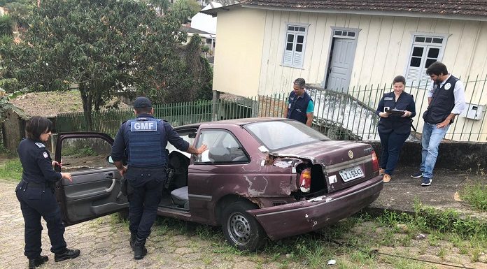 agentes de trânsito em volta de um veículo muito velho e enferrujado parado em uma ladeira
